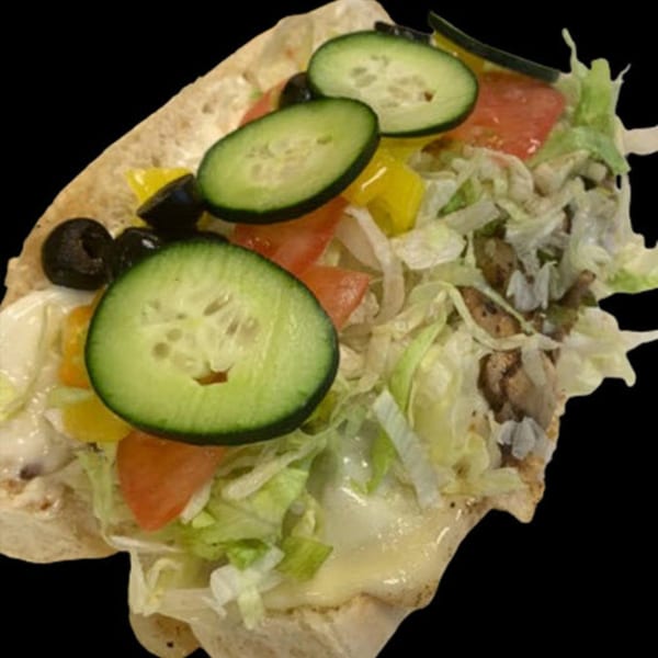 A pita bread sandwich filled with sliced cucumbers, black olives, tomatoes, lettuce, and meat.