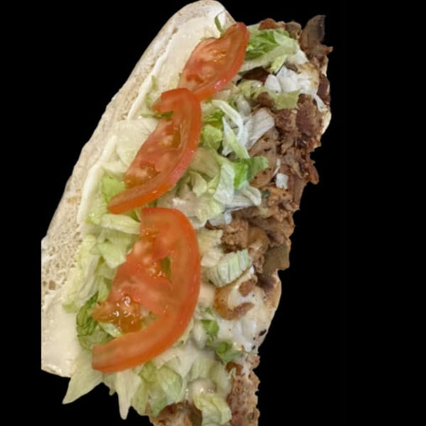A close-up of a STL Steak and Cake cheesesteak sandwich with steak, lettuce, tomatoes, and sauce.