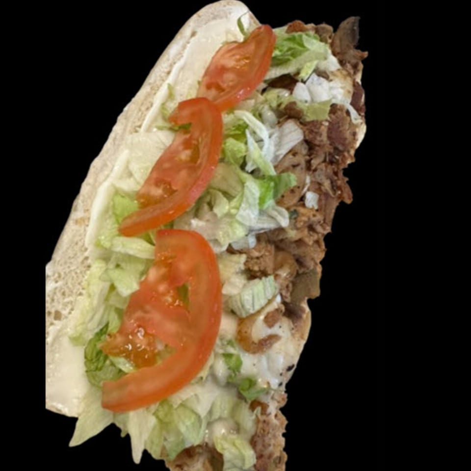 A close-up of a STL Steak and Cake cheesesteak sandwich with steak, lettuce, tomatoes, and sauce.
