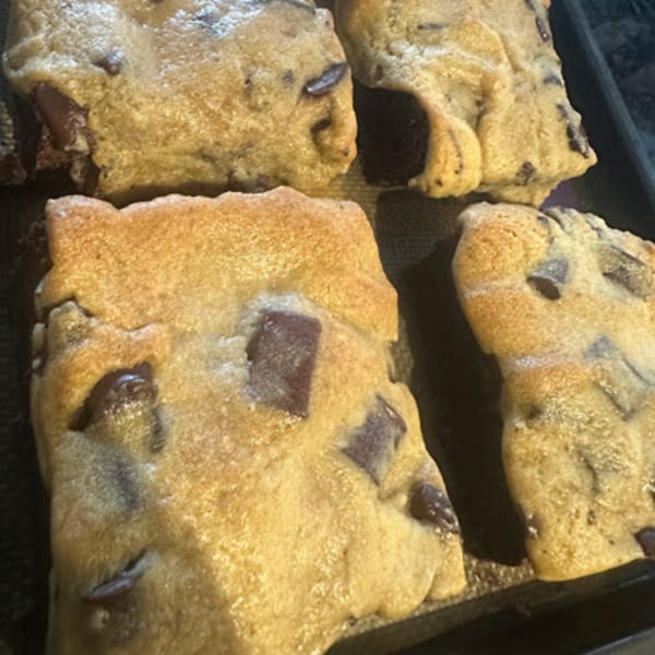 Close-up of several warm, gooey chocolate chip cookies on a baking sheet from STL Steak and Cake.
