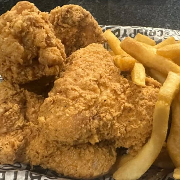 Crispy fried chicken pieces and golden french fries served on branded paper from STL Steak and Cake.