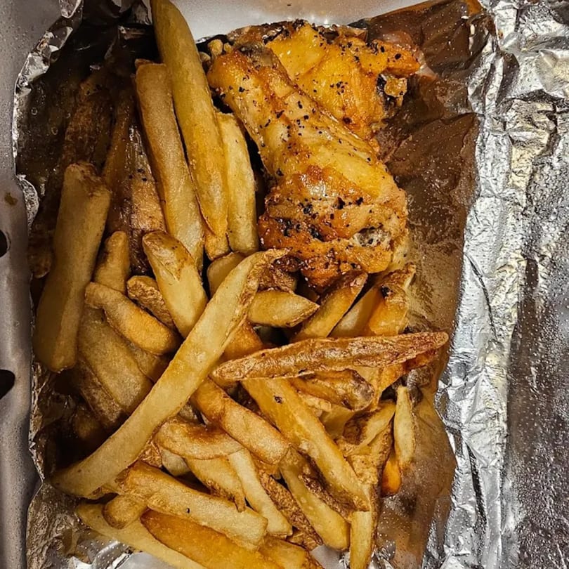 STL Steak and Cake's seasoned chicken wings and crispy french fries in a foil container.