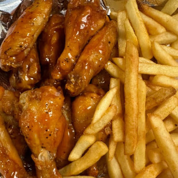 STL Steak and Cake's glazed chicken wings with black pepper and a side of golden french fries.