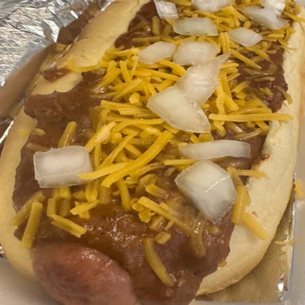 A chili cheese hot dog from STL Steak and Cake, topped with shredded cheddar and diced onions.